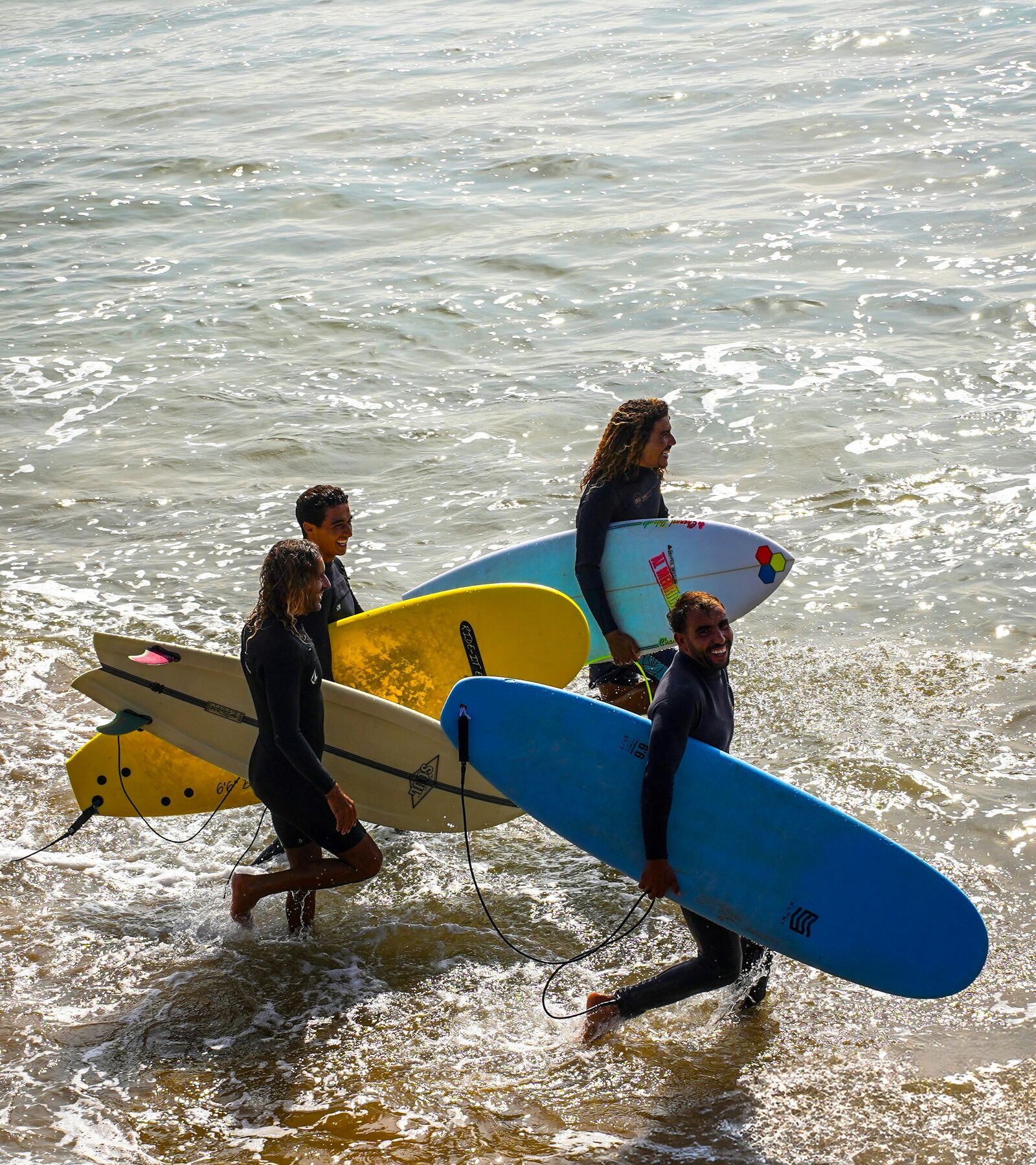 A surf group carrying colorful boards into the ocean